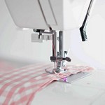 A photo of a sewing machine with some gingham fabric